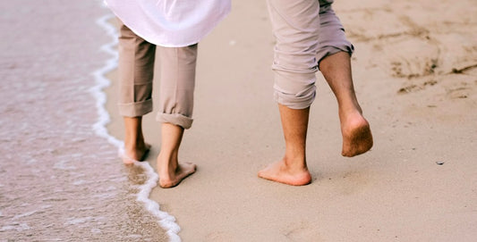 Two people walking barefoot on the beach